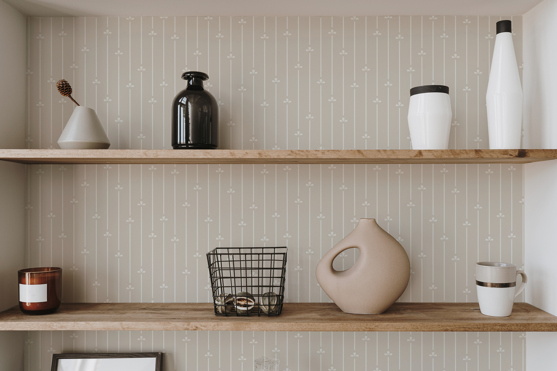 Stylized shelf in neutral tones with modern understated striped wallpaper that has random scattered floral motifs.