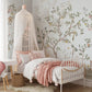 Children's bedroom with pale blue Meadowsong Mural in Reverie colorway, white canopy bed, and pink accents.