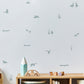 A styled nursery corner featuring light green-toned gray wall decals of ducks, ducklings, pond items and reeds on a white wall above a wooden toy shelf with toys.