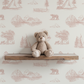 Teddy bear on a wooden shelf with pink outdoors themed wallpaper