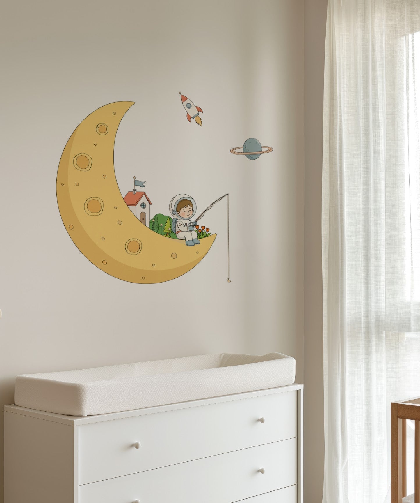 A wall decal featuring a cartoon astronaut fishing from a crescent moon with a small rocket and planet, shown applied to a beige wall above a white dresser in a nursery setting.