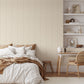 Contemporary style bedroom with neutral warm tones with warm beige wallpaper with thin stripes and scattered motifs.