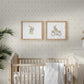 A soft blue floral lattice style wallpaper with a cream background styled in a nursery with a wooden crib and white bedding. 