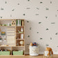 A styled children's room with a light beige wall covered in small dark green duck pond-themed wall decals, including ducklings, river and marsh plants, and flying ducks. A wooden toy storage shelf with bins and books stands on the left, and a white animal-themed storage basket and a plush toy sit on the floor in front.