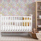 Dainty pink and yellow floral wallpaper with blue accents in a nursery