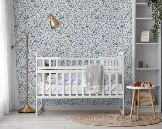 Nursery room with a white crib, blue forest  and floral theme wallpaper, and neutral wooden floor. 
