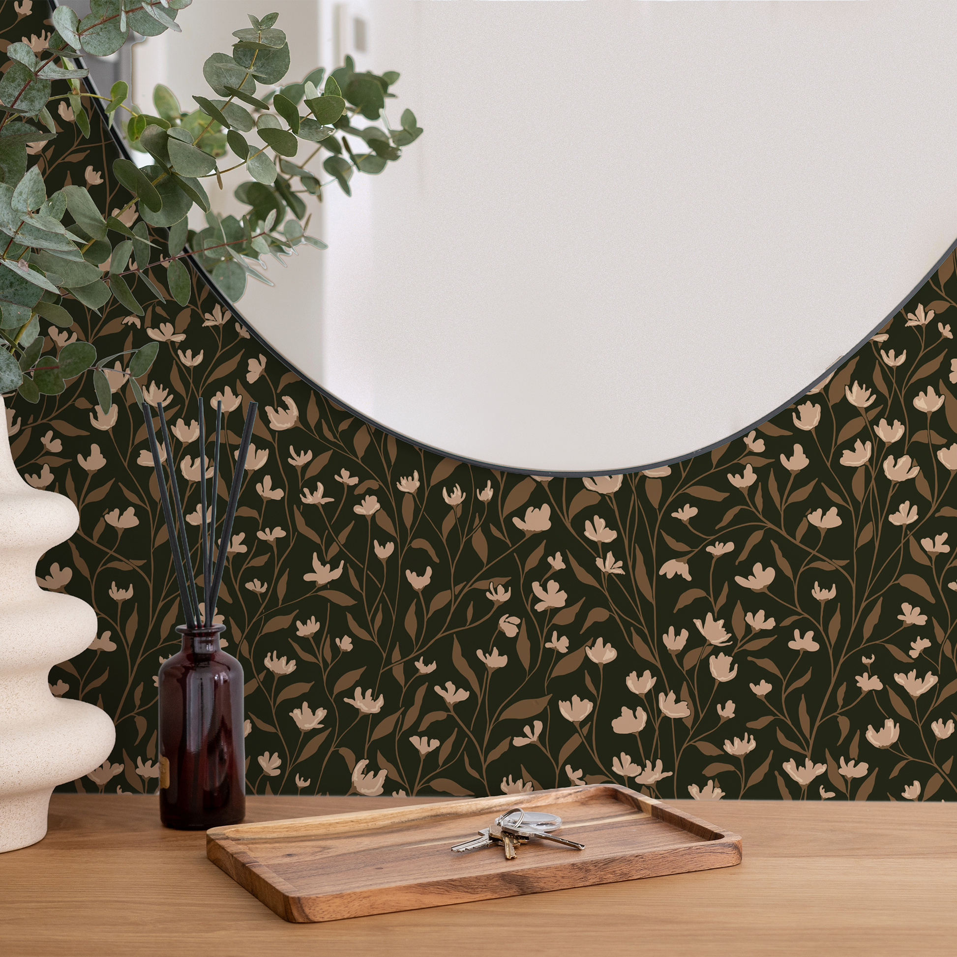 Round mirror with flat stylized overlapping vine wallpaper, wooden tray, and decorative items on a wooden surface.