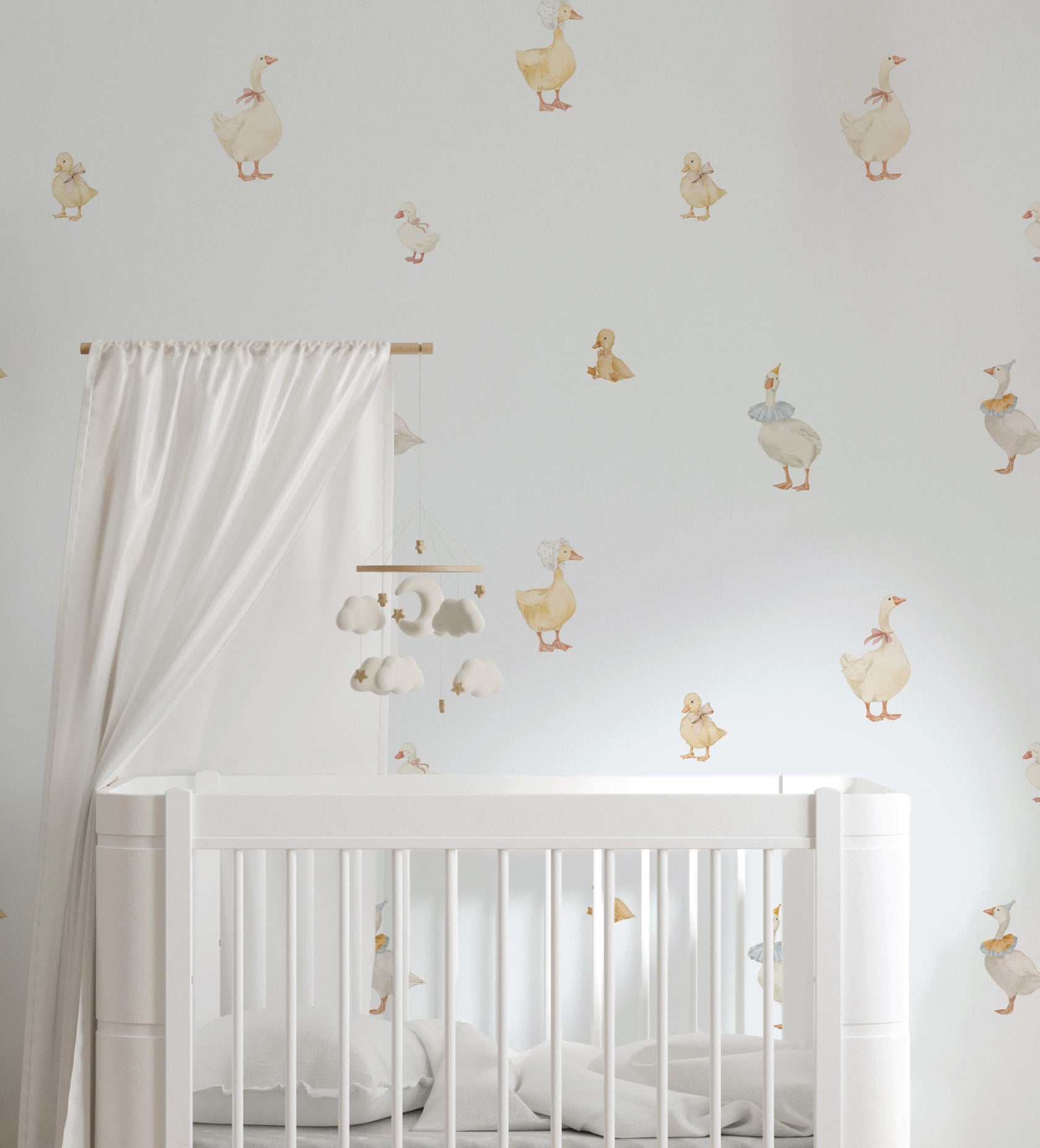A white wooden baby crib in a nursery setting, decorated with whimsical duck and goose wall decals on a light gray wall. A white canopy curtain hangs from a wooden rod on the left, and a matching mobile hangs above the crib.