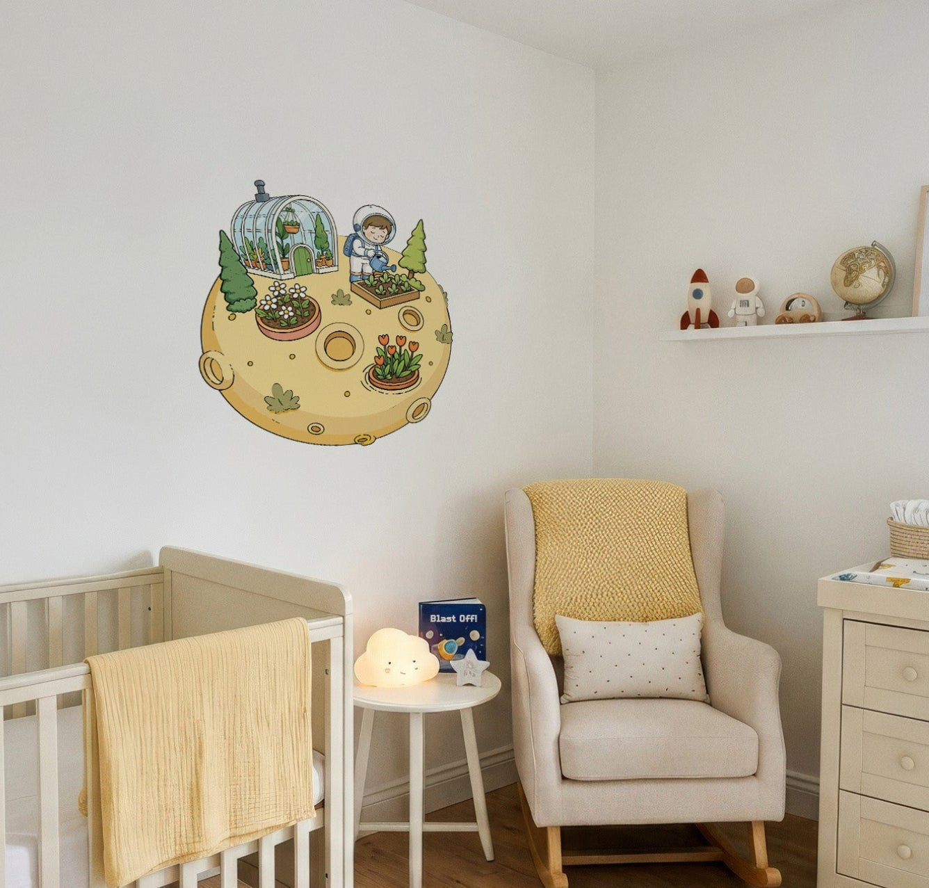 A styled nursery room featuring a whimsical cartoon planet wall decal with a child gardening, displayed on a white wall above a white wooden crib. The room also includes a cream armchair with a yellow blanket, a matching cream dresser, and a small shelf with decorative items.
